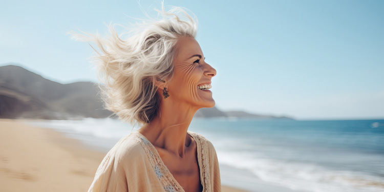 Mature woman experiencing sincere happiness near the blue ocean waters.
