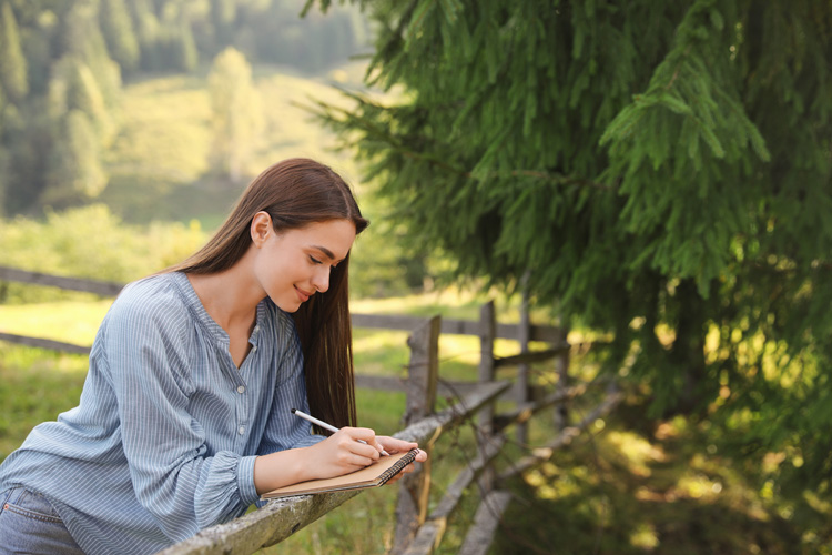 Beautiful young content creator writing in her journal near Laurence Rockerfeller Preserve in Grand Teton. Beautiful young content creator writing in her journal near Laurence Rockerfeller Preserve in Grand Teton.