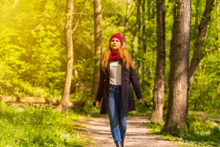 Beautiful young lady taking a gratitude walk on a forest path.