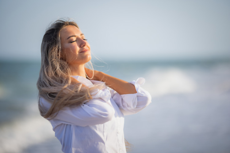 Mature woman enjoying the wellness benefits of the beach.