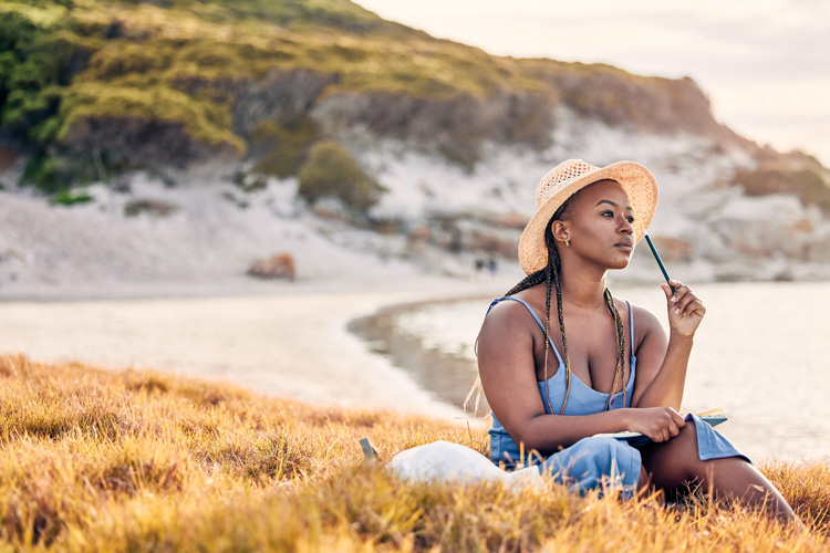 Young African-American woman writes in her journal at the beach. Young African-American woman writes in her journal at the beach.