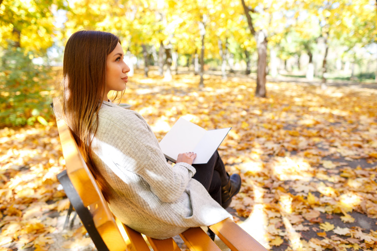 Young woman journaling in park, keeping with the nature therapy in Taos.