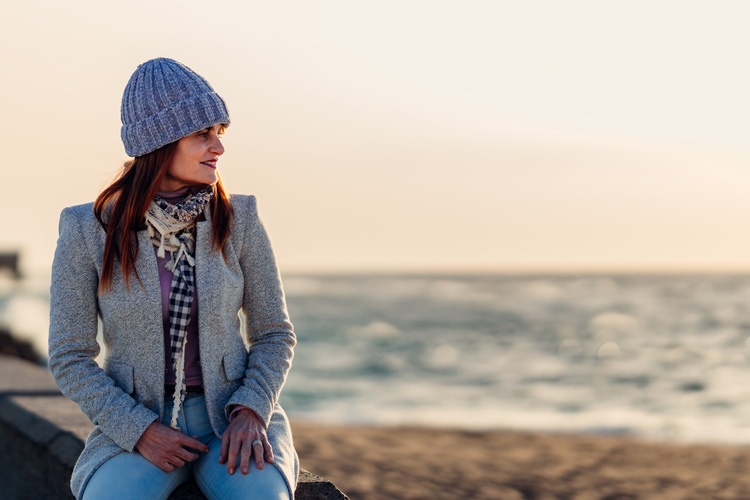 Young woman practices mindfullness moments near the shore during winter. Young woman practices mindfullness moments near the shore during winter.