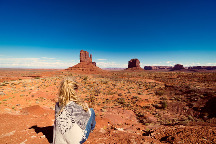 Young woman wrapped in blanket at sunrise in Monument Valley.