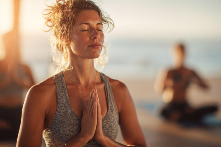 Young woman experiencing the mental benefits of beach yoga.
