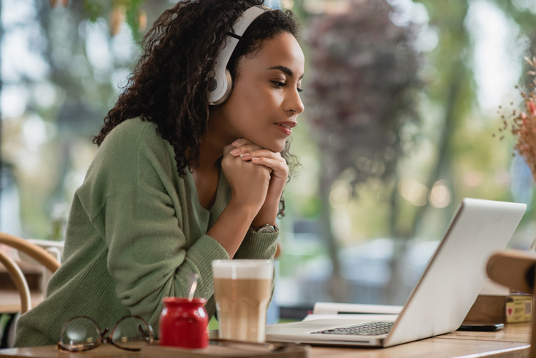 Young African-American woman writer listening to binaural beats in a coffee house. Young African-American woman writer listening to binaural beats in a coffee house.