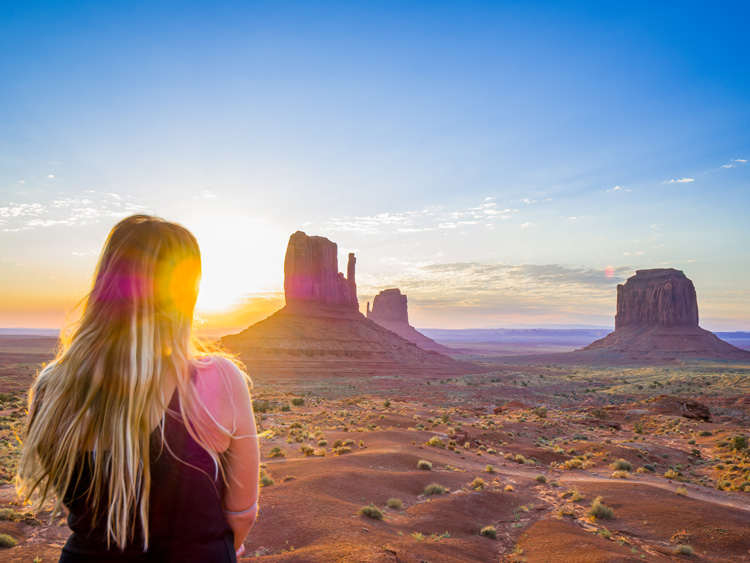 Young woman views sunset over Monument Valley.