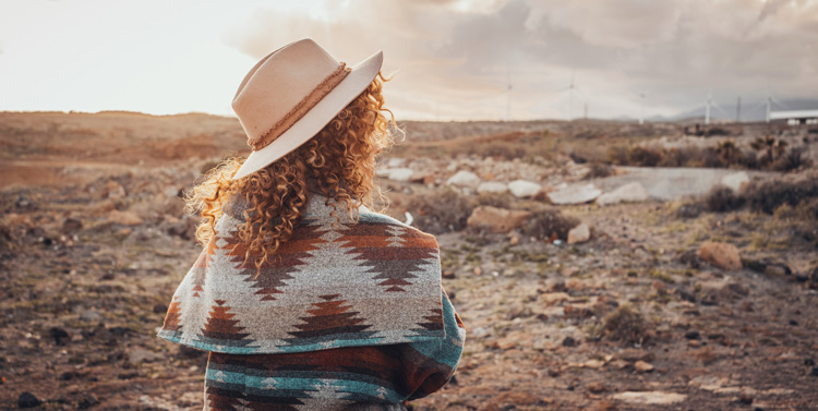 Young woman with the expanse of the high-desert outskirts of Taos New Mexico in front of her.