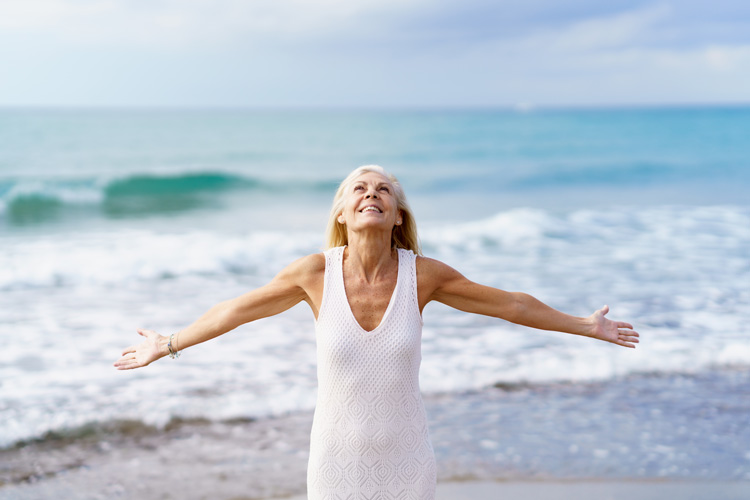 Beautiful mature woman demonstrates a simple beach ritual of thankfulness.