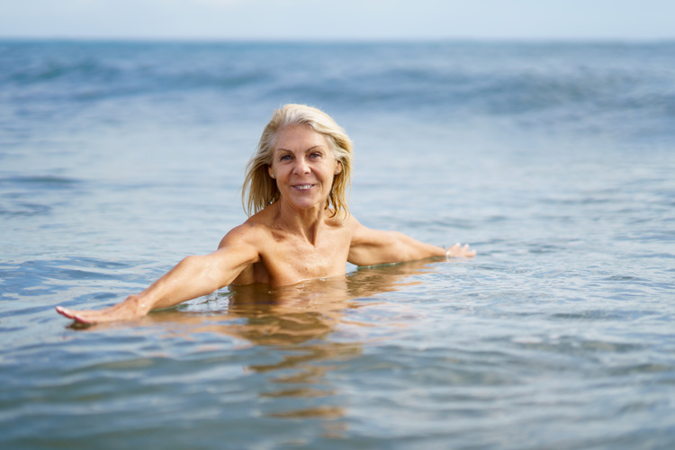 Mature woman thrives in the ocean as she connects with nature the beach.