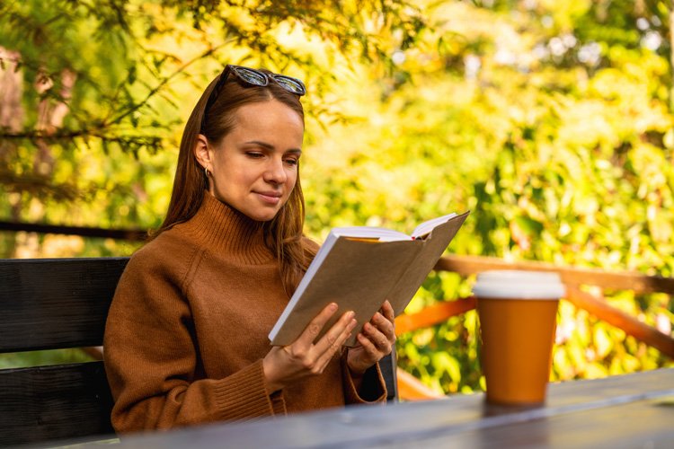 Woman studies book on the science of meditating outdoors in the morning.