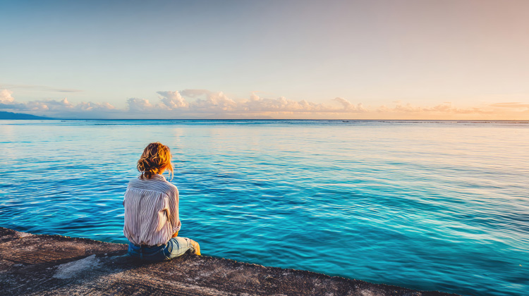 Young woman experiencing blue place stress release near the ocean.