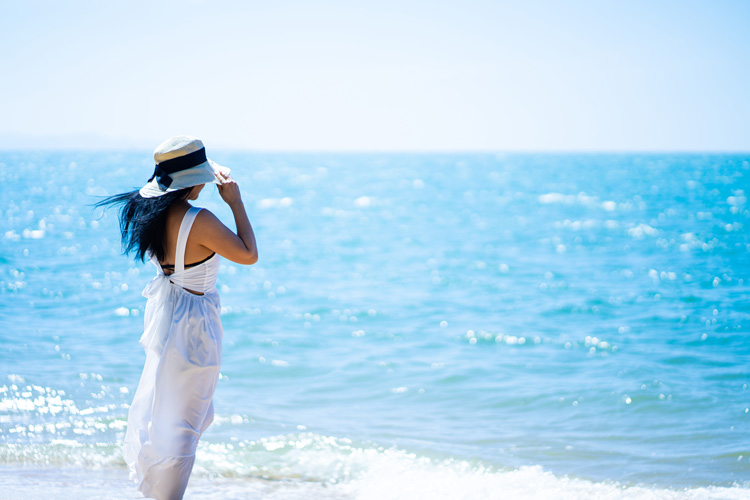 Young woman at seashore for beach blue space therapy.