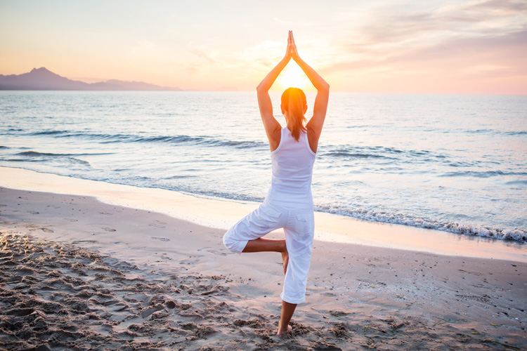Young woman in tree pose experiencing the physical benefits of beach yoga.