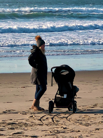 A young mother and her baby visit the beach. Thanksgiving Day on Rockaway Beach OR.